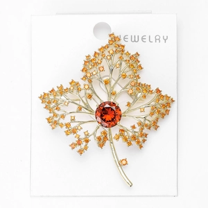 Macro shot of maple leaf brooch featuring a deep red gemstone and yellow zircons