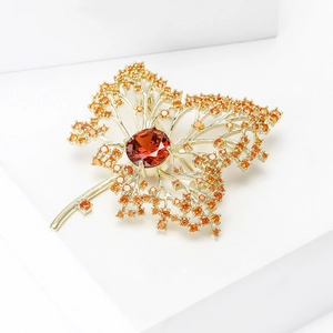 Luxurious gold maple leaf brooch with red center crystal and amber zircon stones