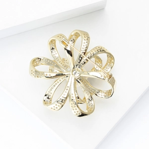 Detailansicht der Rückseite der goldenen Blumenbrosche mit Textur und Sicherheitsnadel