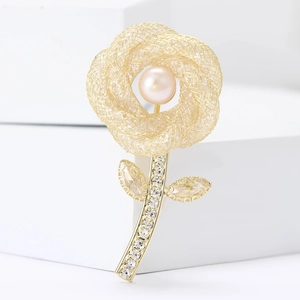 Élégante broche fleur dorée avec perle rose et zircons sur un socle blanc moderne