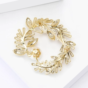 Detailed close-up of a golden leaf wreath brooch featuring white zircon and a large pearl
