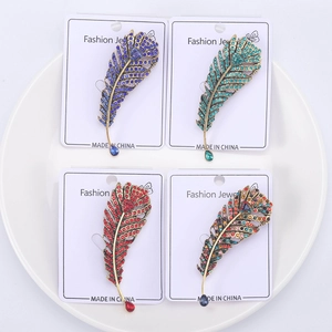 Detailed close-up of four rhinestone feather brooches with colorful teardrop gemstones