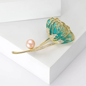 Detail of luxury pearl enamel flower brooch with green petals and golden metallic frame