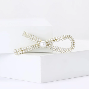 Elegant pearl bow brooch with gold alloy base and white faux pearls on minimalist display
