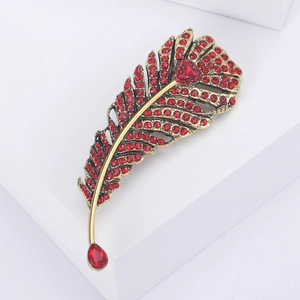Macro shot of the luxury gold feather brooch with radiant red rhinestones and gemstones