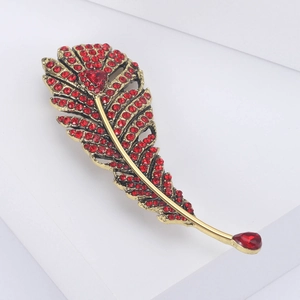 Detailed macro view of a vintage feather brooch with red rhinestones and a gold finish