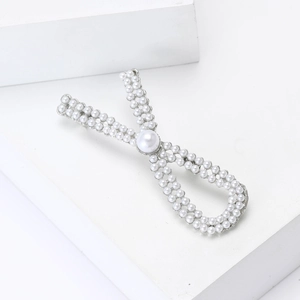 Detailed close-up of an elegant silver pearl bow brooch with a large central pearl