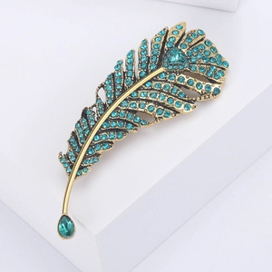 Detailed view of a vintage feather brooch with teal rhinestones and a large teardrop crystal