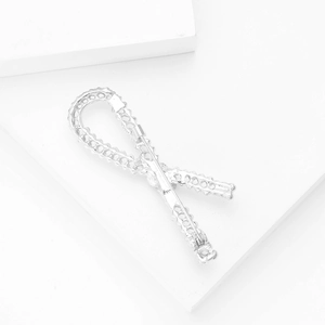 Close-up of sparkling ribbon bow brooch with micro-pave crystals on white block