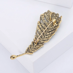 Vintage gold feather brooch with rhinestones and elegant antique metal texture on white