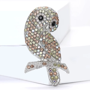 Vista macro della spilla a gufo con strass multicolori su supporti geometrici bianchi