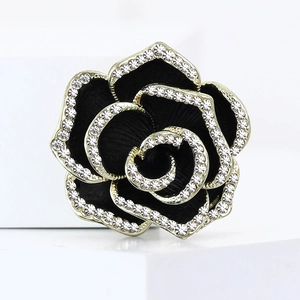 Élégante broche camélia noir avec strass blancs sur un socle géométrique blanc