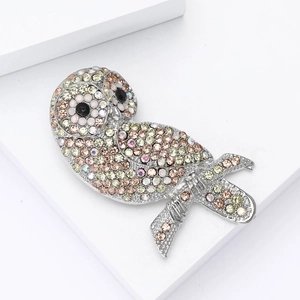 Dettaglio macro della spilla gufo di lusso con strass multicolori su metallo argento