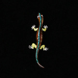 Exquisite gecko brooch in brown enamel with sparkling green crystals on black background