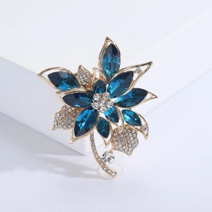 Broche fleur de luxe en cristal avec pierres bleu marine et plaqué or sur un bloc blanc