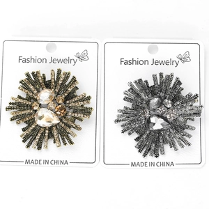 Detail of vintage firework brooches with crystals on display cards in gold and silver