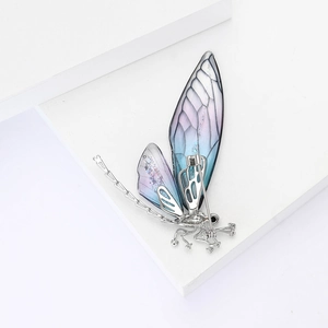 Detail of dragonfly brooch with blue-pink gradient wings on white geometric stand