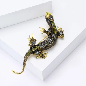 Détail macro d'une broche lézard de luxe avec pierres grises et strass verts sur monture or