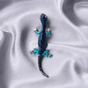 Macro shot of colorful enamel gecko brooch with crystal accents on silk fabric