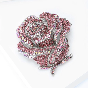 Détail macro d'une broche rose avec strass roses et cristaux irisés sur monture argentée