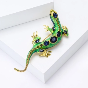 Broche lézard de luxe avec émail vert et gemmes bleues sur un bloc géométrique blanc