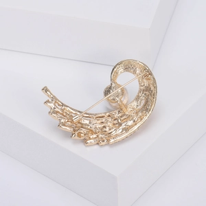 Élégante broche dorée queue de phénix avec perle sur support géométrique blanc