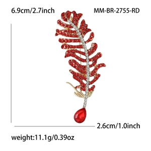 Detailed view of gold feather brooch with red rhinestones and a teardrop gemstone