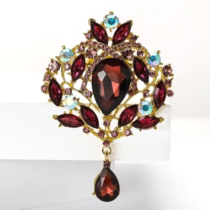 Gros plan détaillé d'une broche vintage en alliage doré avec des cristaux de verre rouge foncé