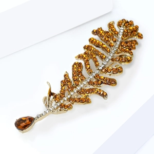 Detail view of gold feather brooch with amber rhinestones and teardrop crystal charm