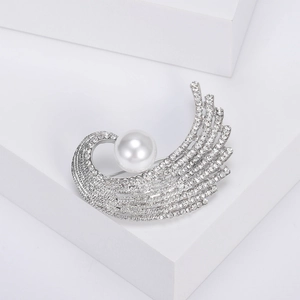 Détail d'une broche aile argentée haut de gamme avec perle centrale et strass brillants