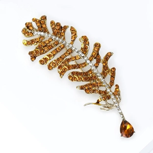 Macro detail of bronze feather brooch with amber rhinestones and water drop gem