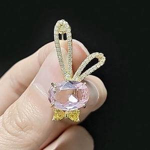 Détail de broche lapin en cristal rose avec placage or et nœud en zircone cubique