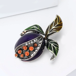 Détail d'une broche grenade vintage avec émail violet et graines en perles oranges