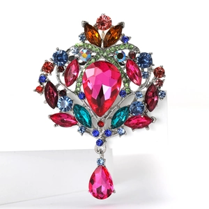 Détail d'une broche vintage avec une grande pierre rose en forme de poire et cristaux