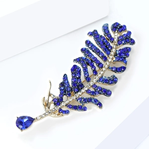 Detailed close-up of feather brooch with blue crystals and a large pear-shaped blue stone