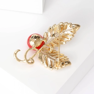 Elegant gold leaf brooch with micro-pave zircons and a large red pearl accent