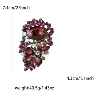 Detail view of a vintage crystal brooch with red gemstones and colorful rhinestones in gold