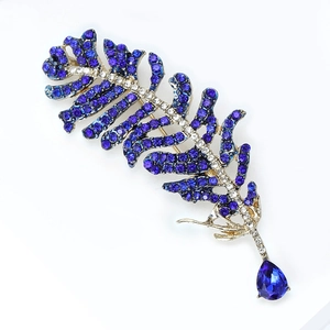 Close-up of silver feather brooch with purple crystals and pear-cut blue gemstone