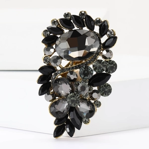 Detail einer Vintage-Brosche mit grauen Kristallen und schwarzen Strasssteinen auf Gold