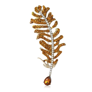 Exquisite golden feather brooch with amber rhinestones and crystal accents on white background