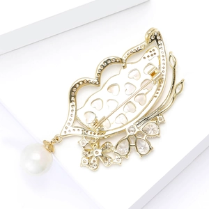Detail view of gold butterfly brooch featuring micro-set zircon and pearl pendant