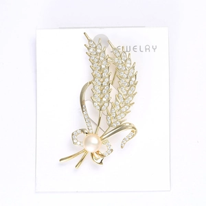 Détail d'une broche épis de blé dorés avec cristaux pavés et perle rose élégante