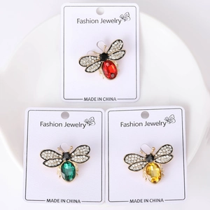 Close-up of cute bee brooches with red, green and yellow crystals on white display cards