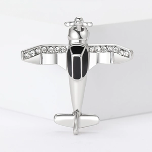 Detailed view of silver aircraft brooch with white rhinestones and black enamel accents
