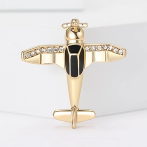 Golden airplane brooch with black enamel and rhinestones on white marble base