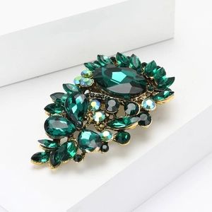 Elegant gold-plated brooch with emerald green faceted stones and iridescent crystals