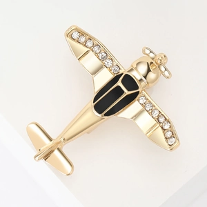 Detail of a gold aircraft brooch with sparkling white rhinestones and black enamel