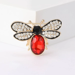 Macro view of gold honeybee brooch featuring red gemstone and crystal wings details
