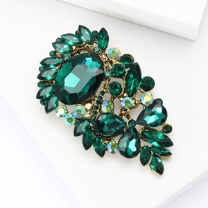 Detail shot of vintage gold brooch with emerald cut stone and marquise crystals