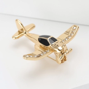 Detailed view of a gold-plated airplane brooch with rhinestones and black enamel finish